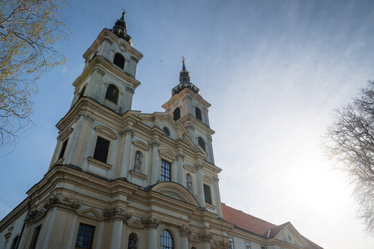 Low angle view of a baroque Basilica of the Seven Sorrows of the Blessed Virgin Mary with twin ornate towers and classic stone facade under a bright sunny sky, Sastin-Straze, Slovakia