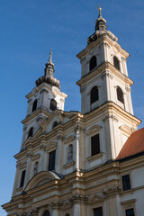 Fototapeta premium Low angle view of a baroque Basilica of the Seven Sorrows of the Blessed Virgin Mary with twin ornate towers and classic stone facade under a clear sky, Sastin-Straze, Slovakia