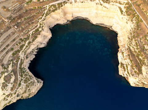 Aerial view of the rugged Sanap Cliffs meeting the deep blue sea, where the sun kisses the pale stone, Munxar, Gozo, Malta.