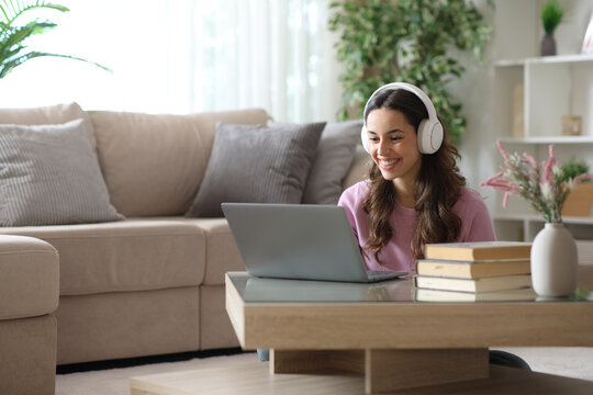 Happy woman wearing headphone watching media on computer