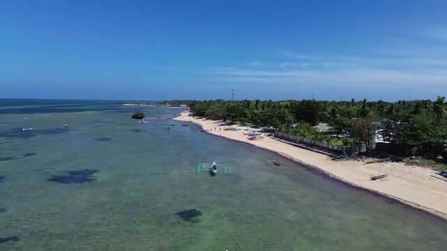 Aerial view of a pristine tropical beach with palm trees and turquoise water surrounded by dense green vegetation creating a peaceful and untouched coastal landscape on Bantayan Island Philippines