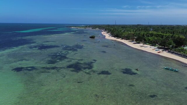 Aerial view of a tropical island coastline with white sand beach clear ocean water and dense green vegetation creating a pristine and untouched landscape on Bantayan Island Philippines Southeast Asia