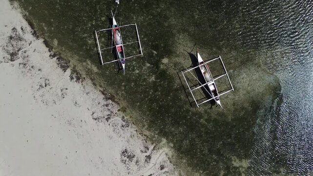 Top Down rise up Aerial view of traditional Bangka boats floating on calm tropical sea with clear water creating a peaceful minimal coastal scene around Bantayan Island Philippines Southeast Asia