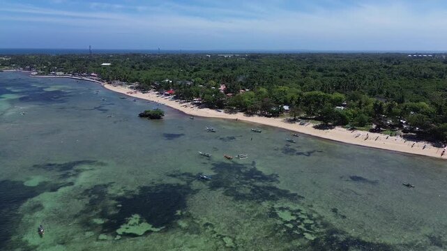 Aerial view of a tropical island coastline with white sand beach clear ocean water and dense green vegetation creating a pristine and untouched landscape on Bantayan Island Philippines Southeast Asia