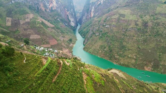 Aerial drone footage of massive limestone cliffs rising above a narrow river carving through a deep canyon showcasing powerful geological formations and raw natural terrain