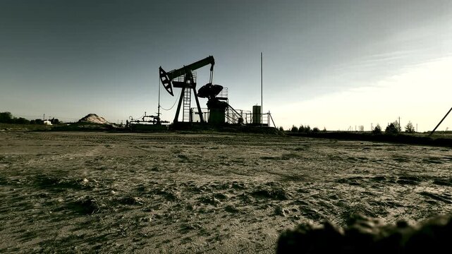Oil Pump Jack Operates during northern lights at Oil Field in Industrial Area. Crude pump jack working on sunrise in oil field. Oil drill rig, drilling derrick in oilfield. Crude petroleum industry. 