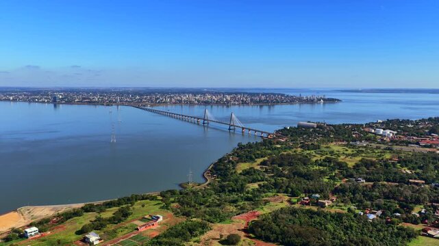 Breathtaking aerial footage of the Puente Internacional San Roque Gonz&aacute;lez de Santa Cruz, linking Posadas, Argentina, and Encarnaci&oacute;n, Paraguay over a serene river. Bright, clear day.