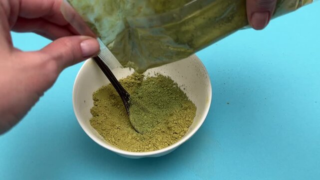 Female hands pour henna powder from bag into bowl closeup