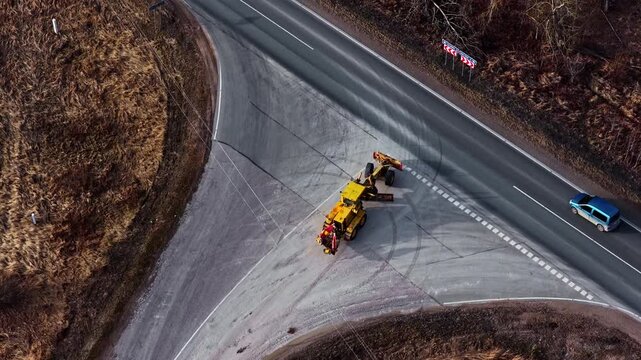Road grader turning on highway after finished work on gravel road, aerial view