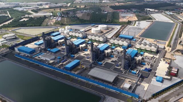 Expansive aerial footage showcasing a modern natural gas power plant, highlighting its complex infrastructure, turbines, cooling towers, and storage tanks for efficient energy generation