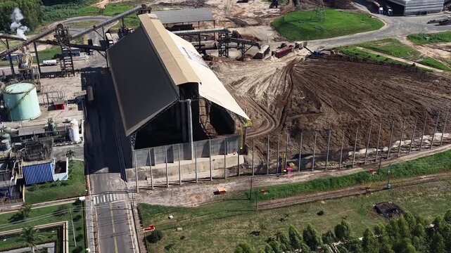 Aerial video footage of a large industrial construction site with a massive building and dirt pile