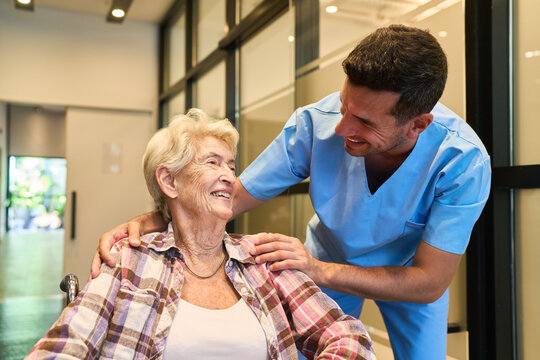 Healthcare professional assisting elderly woman in wheelchair with a cheerful smile