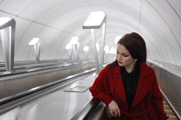 Obraz premium Stylish brunette climbing an escalator from a light-toned modern subway station