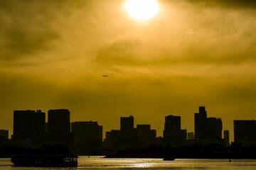 Obraz premium Silhouetted Tokyo skyline under a dramatic golden sunset in Odaiba, Japan