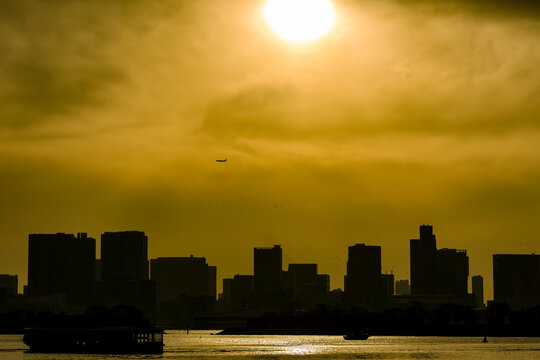 Silhouetted Tokyo skyline under a dramatic golden sunset in Odaiba, Japan