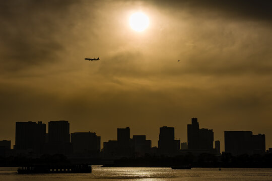 Wide shot of Odaiba, Tokyo skyline silhouetted against a bright sunset sky