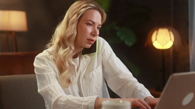 Refined Woman Efficiently Handles Phone Calls And Laptop Tasks At Home. Sophisticated Woman Smoothly Juggles Phone Conversations And Computer Responsibilities Within Her Home Workspace