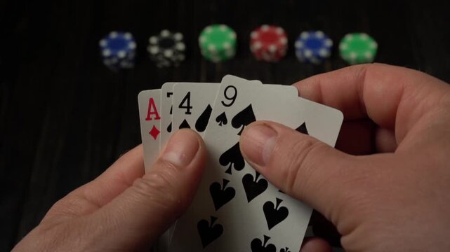 Player reveals a hand of spade cards and ace or high card, starting with a single card and progressing to a full hand, with colorful poker chips arranged in the background