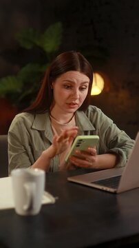 Vertical portrait of focused woman browse products in internet online shopping store planning trip travel or swiping through profiles on dating app on smartphone at home Choice concept