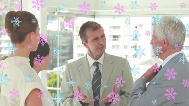 Pink and blue snowflakes icons floating over diverse businesspeople discussing together at office
