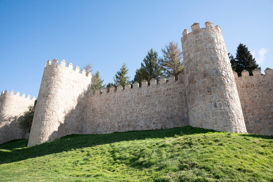 Historic stone walls with towers and greenery.. Walls of &Aacute;vila in Spain