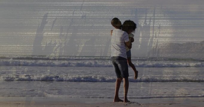 Father lifting daughter off sand, rotating and swinging her near waves, showing bonding for health