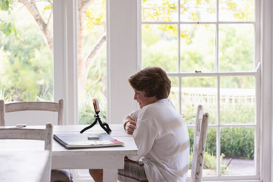 12 year old boy using smart phone on tripod at home