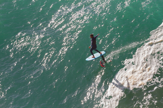 High angle view of a man hydrofoil surfing on turquoise ocean water.