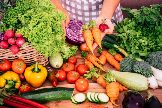 Fresh colorful vegetables at a farmers market stall with hands holding carrots and radishes