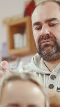 Male hairdresser concentrating while airbrushing female customer hair