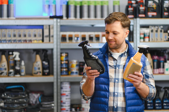 Man comparing car care spray products in store