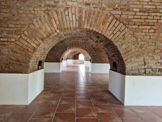 Fototapeta premium Historic Corridor with Red Brick Arches and Terracotta Tiled Floor