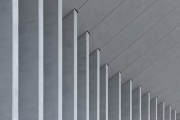 Fototapeta premium Row of vertical concrete columns recedes in perspective along modern building facade. Repetition creates strong linear rhythm and depth in architectural composition. Concept of minimal design,