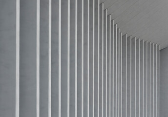 Fototapeta premium Tall architectural columns rise in repeating sequence along curved modern structure. Vertical elements create dynamic rhythm across exterior surface of building. Concept of contemporary design,