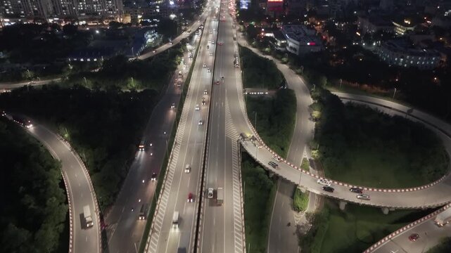 Top down night aerial of Phap Van Cau Gie expressway interchange in Hanoi with illuminated lanes, smooth traffic flow, and curved ramps forming dynamic geometry