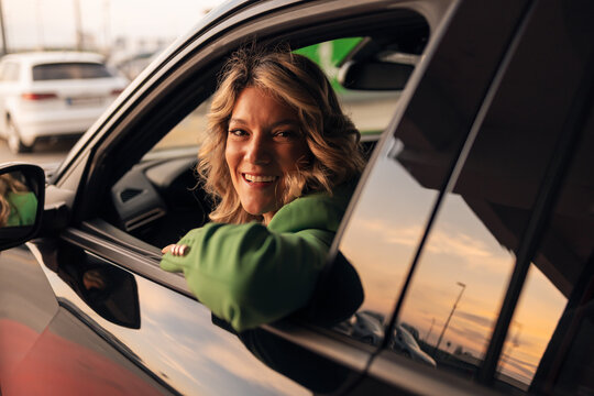 Happy woman enjoying freedom driving car during golden hour
