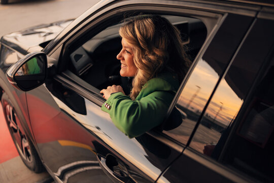 Woman smiling driving car enjoying sunset light