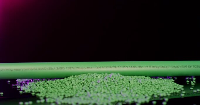 Close up of green industrial plastic pipe with technical specifications resting on a pile of polymer granules