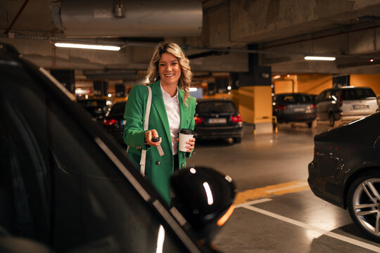 Smiling woman unlocking car in underground parking garage