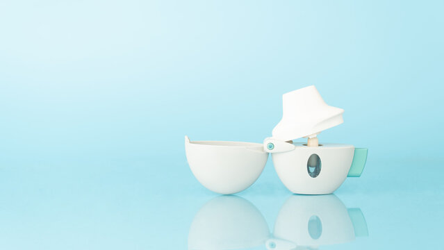 Asthma and COPD concept. Tiotropium bromide inhaler with reflection on light blue background. Pharmaceutical device of bronchodilator for lung inflammation treatment and prevent asthma attack.