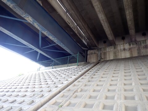 Bridge inspection: Underside of a highway bridge showing steel and concrete girders and abutment