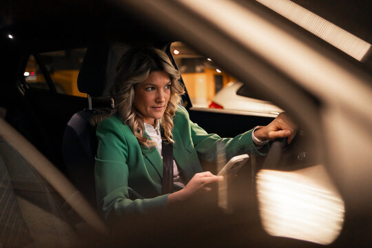 Woman driving car at night using cellphone distracted