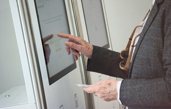 Elderly person interacts with touchscreen to request medical service at Health center.