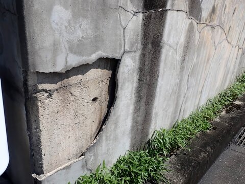 Concrete delamination: A large section of surface peeling away from a retaining wall