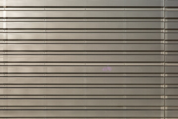 Obraz premium This image features a horizontal high-angle shot of a beige perforated metal surface with parallel ridges and visible mounting bolts.