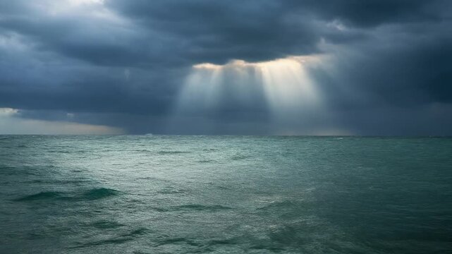 Dramatic god rays of sunlight piercing through dark storm clouds over restless ocean waves for powerful nature and spiritual atmosphere photography concept