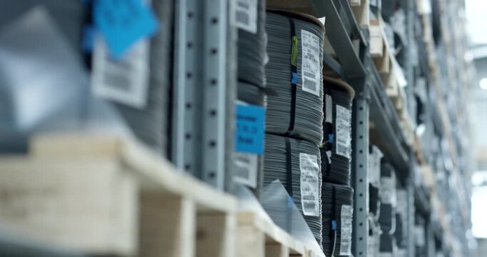 Close up of organized industrial warehouse shelving with stacked metal components and barcode labels
