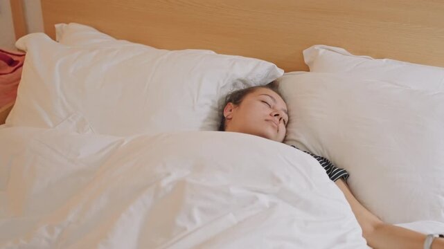 Hotel suite midday guest in deep nap, wellness retreat vibe, soft duvet and fluffed pillows, sunlit headboard, peaceful stillness, bedside watch visible, quiet restorative atmosphere