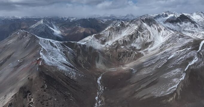 Aerial footage of beautiful high altitude snowcapped mountains and forest landscape