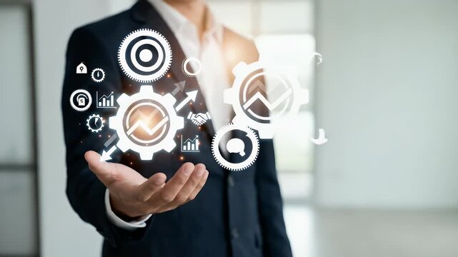 Mid-shot of a professional in a suit holding their hand out to support a glowing white mechanical gear icon connected to business management symbols, static framing with studio lighting and lens flare